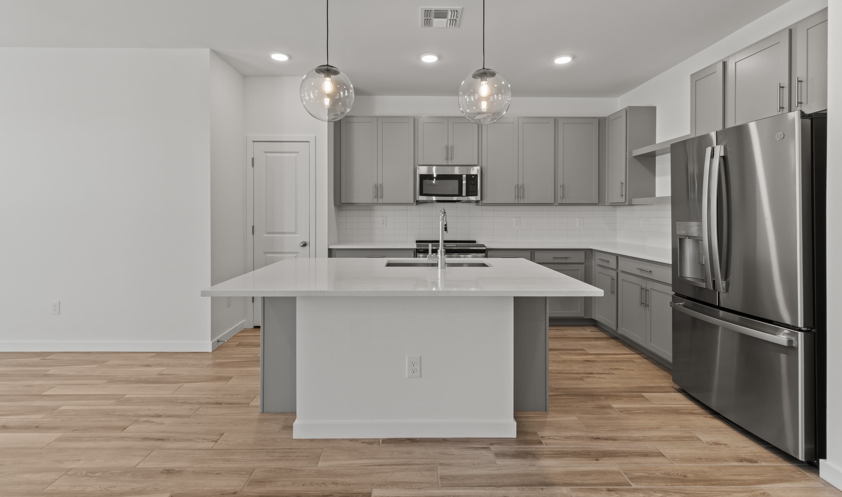 Kitchen with gray cabinets brushed satin nickel finishes