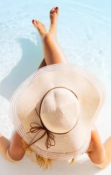 Woman Lounging by Pool in Sun Hat Aerial